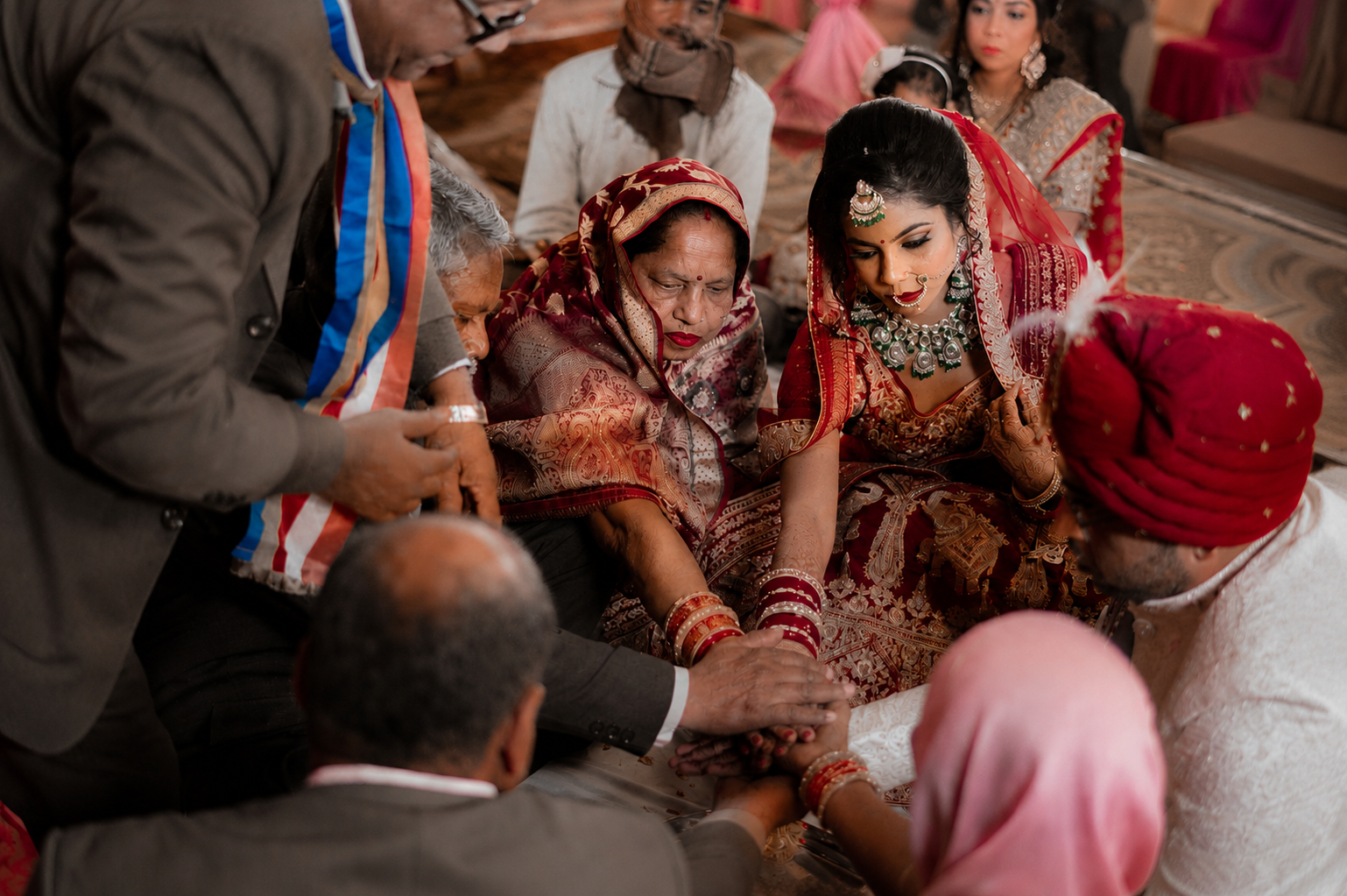 Family hands gathered over the bride's during a sacred ceremony